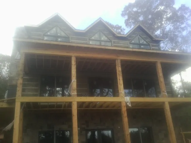 Dormers and porch framing on a large log home under construction — Roof Coating work by our crew in Summerville