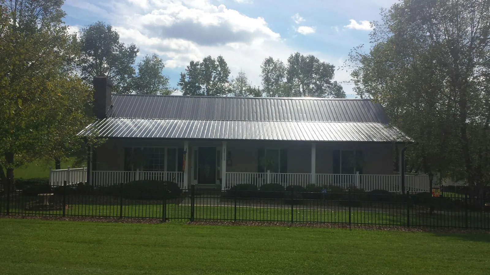 Gray metal roof on a brick ranch with a full width front porch — Gutter Guard Installation work by our crew in Summerville