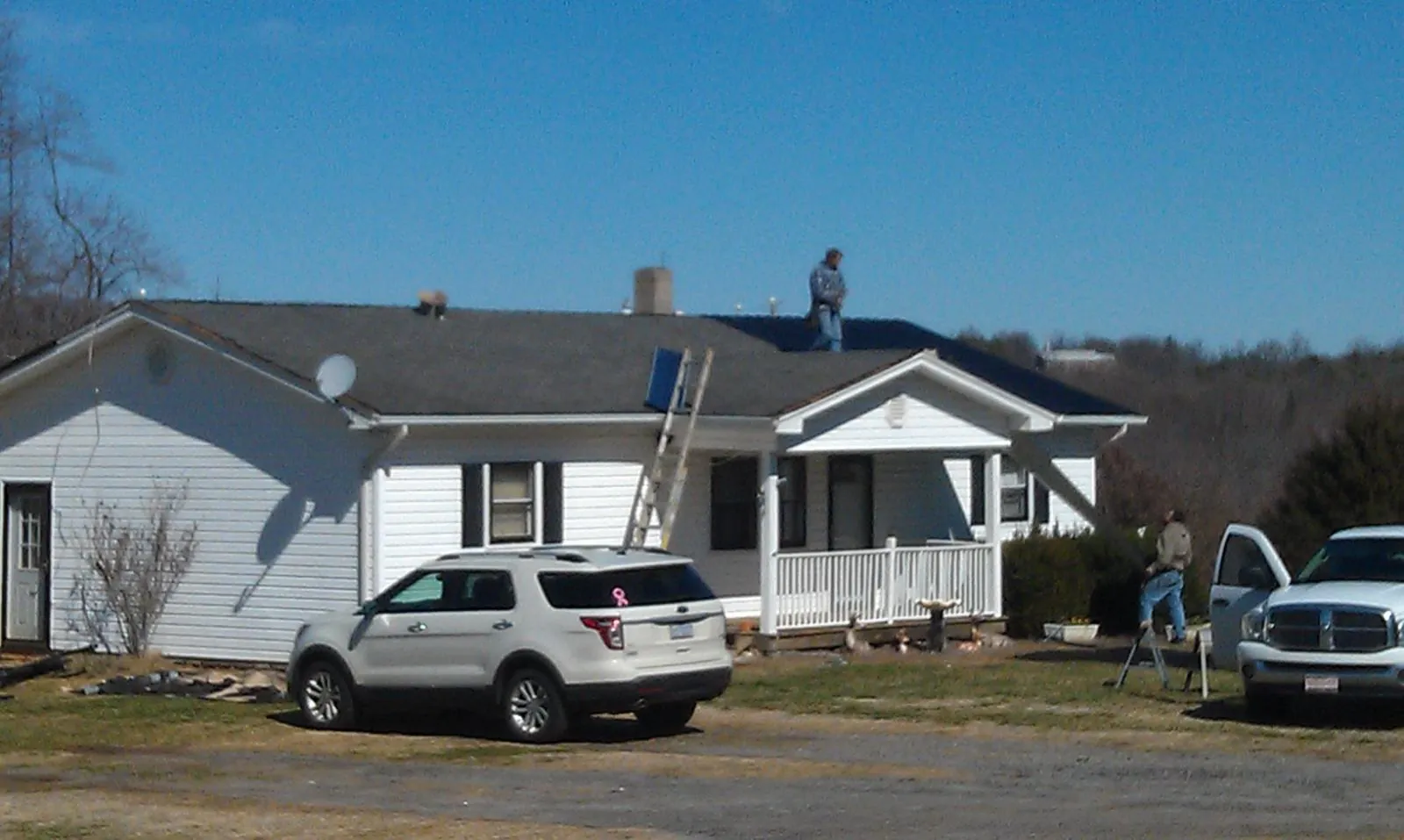 Roofers stripping shingles from a white ranch house roof in Summerville