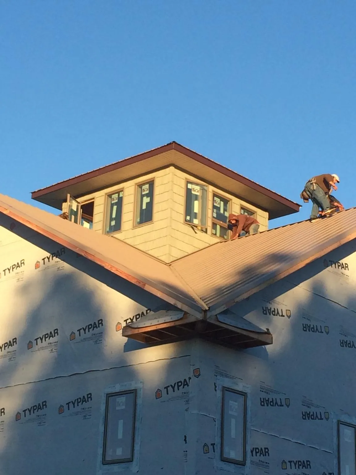 Roofers working around a rooftop cupola on a new metal roof at sunset — Roof Waterproofing in Summerville by Roofing Brothers